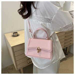 Borsa a tracolla rosa con fibbia dorata mostrata su modella in un ambiente interno caldo
