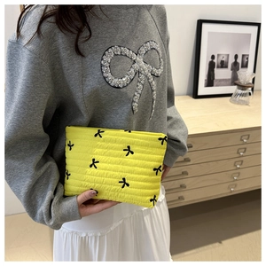 Detailed close-up of quilted yellow cosmetic bag with black bow print on soft fabric