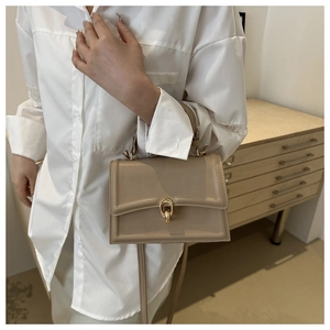 Dettaglio della borsa a tracolla in pelle beige con fibbia ovale dorata e tracolla sottile