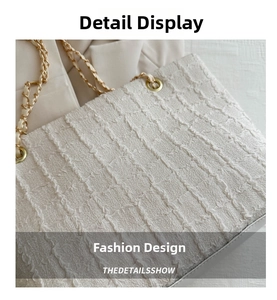 Détail du sac cabas blanc texturé avec tissu plissé vertical et bandoulière dorée
