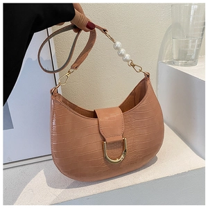 Detail of pink hobo bag with crocodile texture, gold horseshoe buckle and pearl strap
