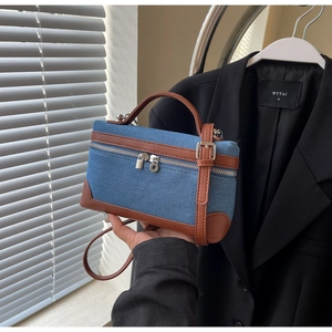 Macro view of blue denim and brown leather contrast stitching on structured box bag