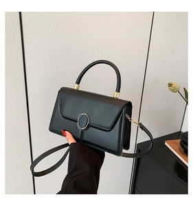 Minimalist black leather handbag for women featuring a gold clasp and top handle