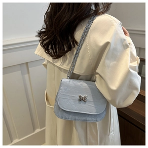 Detail of light blue pleated leather saddle bag with silver butterfly clasp and chain strap