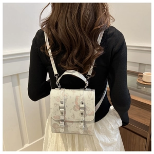 Detail of white backpack with pink butterfly and star prints worn by a model in a cafe