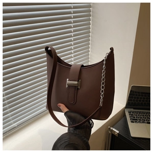 Close-up of retro brown half-moon underarm bag with metal buckle and chain strap