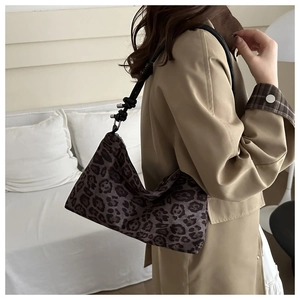 Detail of dark leopard print canvas shoulder bag with black knotted strap on model