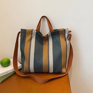 Sac fourre-tout en toile à rayures verticales marron et bleu sur une table en bois