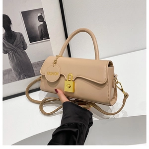 Detailed shot of beige leather crossbody bag with gold hardware and fashion tag