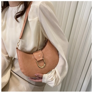 Close-up of pink crescent underarm bag featuring crocodile texture and golden D-buckle