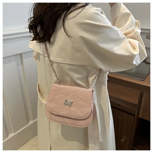 Detail of light pink shoulder bag featuring silver butterfly clasp and crinkled texture