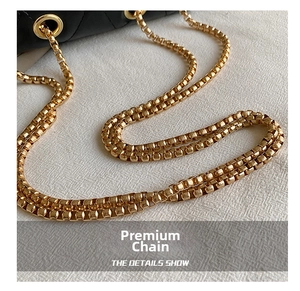 Detailed macro view of the premium gold chunky chain strap on a black quilted leather bag
