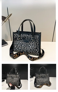 Detail of grey leopard print tote bag with black handles and wide geometric strap