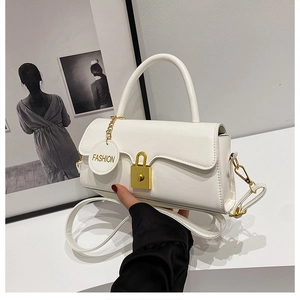 Detail of white matte leather crossbody bag with gold buckle and fashion pendant charm