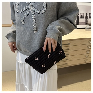 Détail de la trousse cosmétique matelassée noire avec broderie de nœud rose