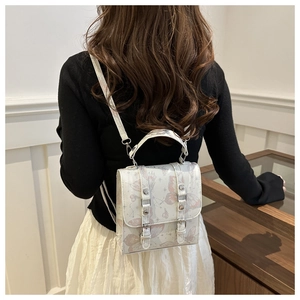 Detail of a butterfly print crossbody bag featuring vintage straps and a cream base color