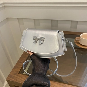 Chic silver trapezoid crossbody bag with a metallic bow detail for elegant styling