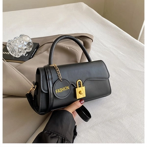 Close-up of black leather crossbody bag featuring gold lock detail and fashion charm