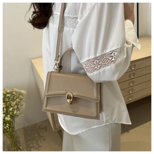 Dettaglio di una borsa a tracolla in pelle beige con fibbia a doppio anello dorato
