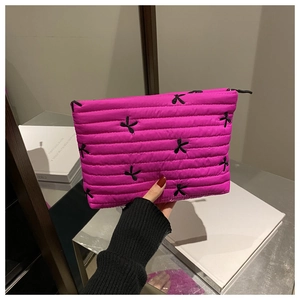 Gros plan détaillé de la pochette matelassée rose avec broderies nœuds noirs