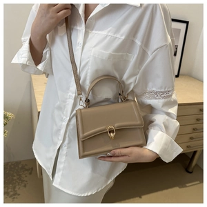 Dettaglio mini borsa quadrata in vernice beige con chiusura ad anello dorato e tracolla