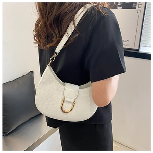 Detail view of white crescent bag featuring crocodile texture and golden horseshoe buckle