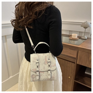 Lifestyle shot of white crossbody bag with purple butterfly prints and metal buckles