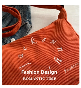 Detail of orange corduroy fabric with white fashion embroidery on casual crossbody bag