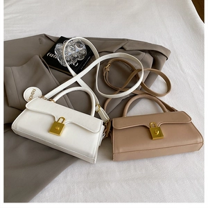 Detailed shot of retro matte PU leather crossbody bags with gold hardware on a grey blazer