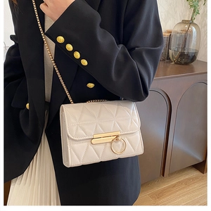 Detail of ivory quilted leather crossbody bag with elegant gold ring clasp and chain