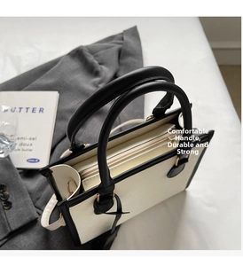 Dettaglio della borsa tote bicolore con manici neri e chiusura con cerniera sicura