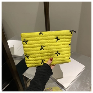 Gros plan détaillé de la trousse à maquillage jaune matelassée avec broderie papillon