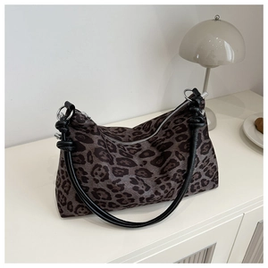 Detail of vintage leopard print tote bag with black handles on a white minimalist shelf