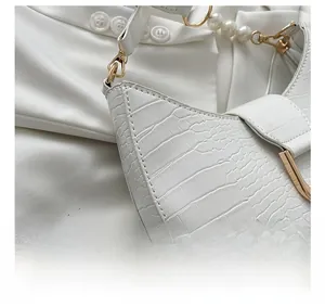 Detail of white crocodile pattern crescent bag with pearl strap and gold buckle