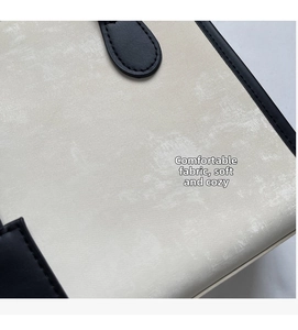 Dettaglio ravvicinato della pelle sintetica beige e delle cuciture nere della borsa tote