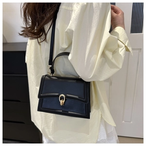 Borsa a tracolla nera chic con fibbia dorata abbinata a camicia beige