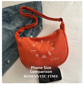 Detailed texture of orange corduroy crescent bag with white embroidered circular logo