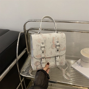 Modern white handbag with butterfly print and silver buckles in a stylish setting