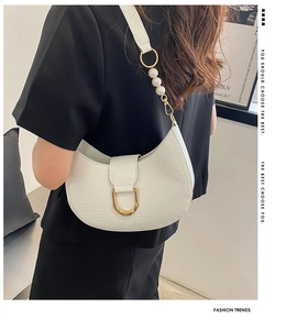 Detail of white crocodile embossed crescent bag with gold buckle and pearl strap