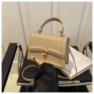 Dettaglio mini borsa beige con fibbia ad anello dorata su una sedia nera moderna