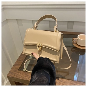 Dettaglio ravvicinato di una borsa squadrata color crema con chiusura dorata intrecciata