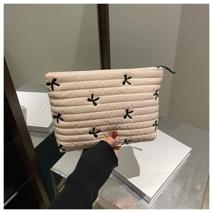 Détail de la trousse de maquillage beige en velours côtelé avec broderie papillon noir
