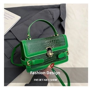 Detail shot of green crocodile-patterned crossbody bag with a golden square lock clasp
