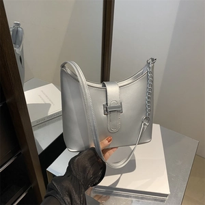 Silver crescent shoulder bag with metallic finish and chain strap in a modern mirror setting