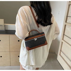 Detail of denim crossbody bag with brown leather trim carried by a model in casual style