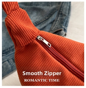 Close-up of smooth metal zipper and vertical corduroy texture on orange tote bag