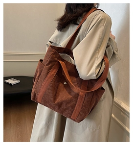 Brown corduroy tote bag shown on shoulder, highlighting its large capacity and texture