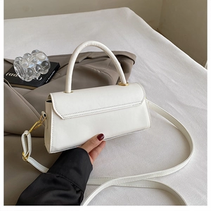 Close-up of minimalist white leather crossbody bag with elegant gold metal hardware detail