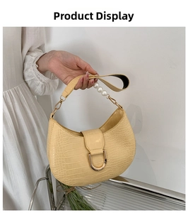Detail of yellow crocodile pattern hobo bag with pearl strap and gold horseshoe buckle