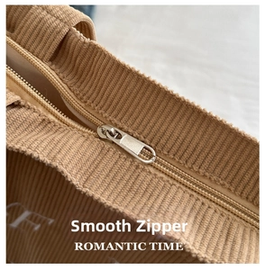 Close-up of smooth silver metal zipper on khaki corduroy tote bag with white lettering